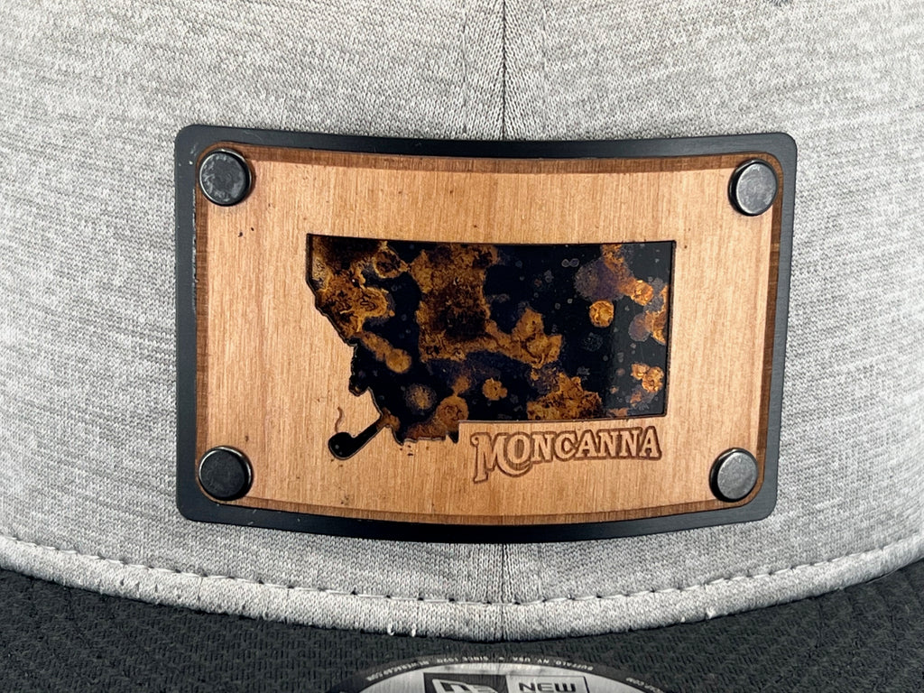 A close up of a wood plate patch with a copper underlay featuring the logo of Moncanna
