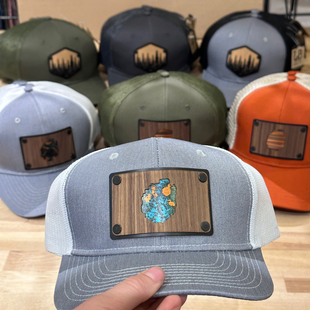 A custom trucker hat with a walnut wood and copper plate patch of the adirondack state park