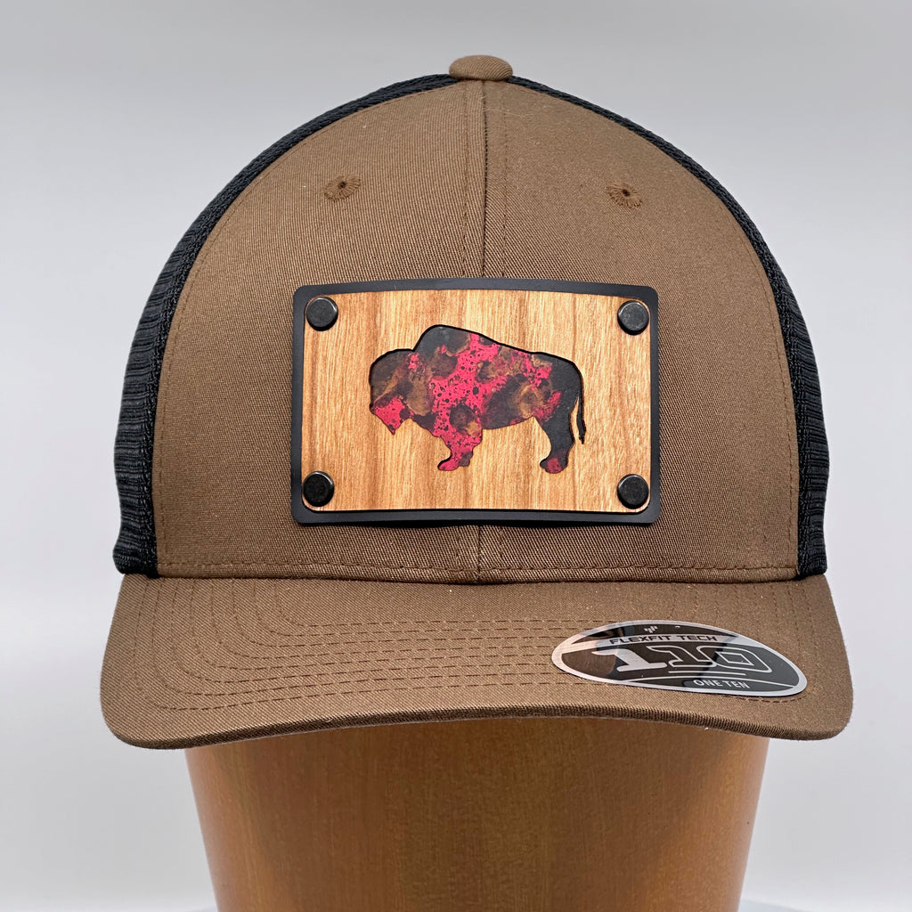 A bison silhouette cherry wood and red copper plate patch riveted to a brown and black flexfit trucker hat.