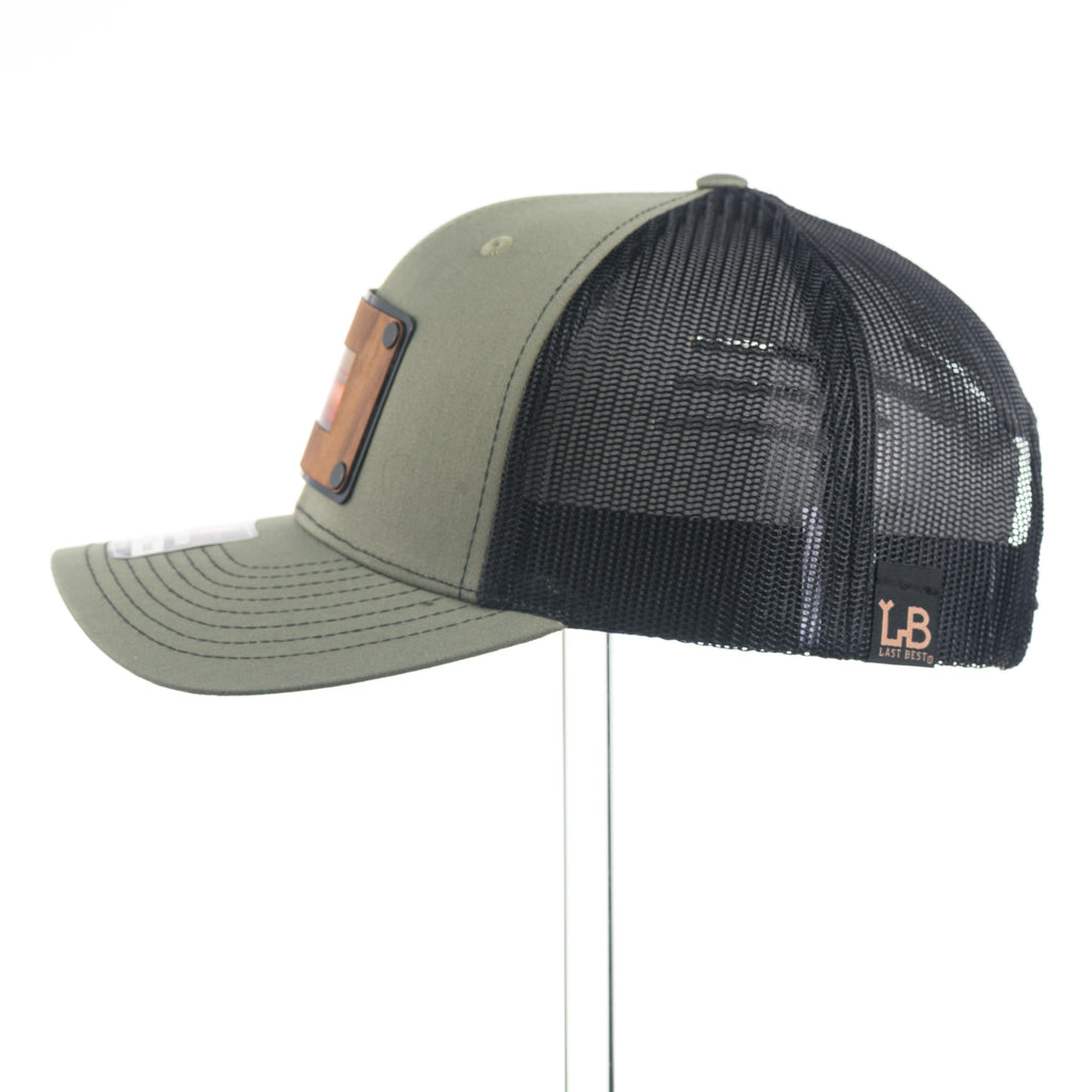 Side view of a Green and black richardson trucker hat with a wood and copper patch