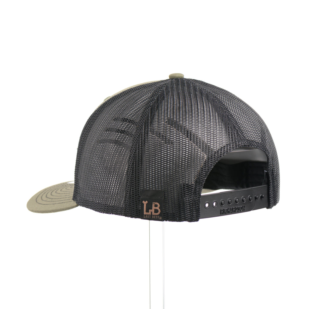 The back of a loden green and black mesh Richardson trucker hat with an etched walnut wood American flag and bison cut out on a black metal patch.