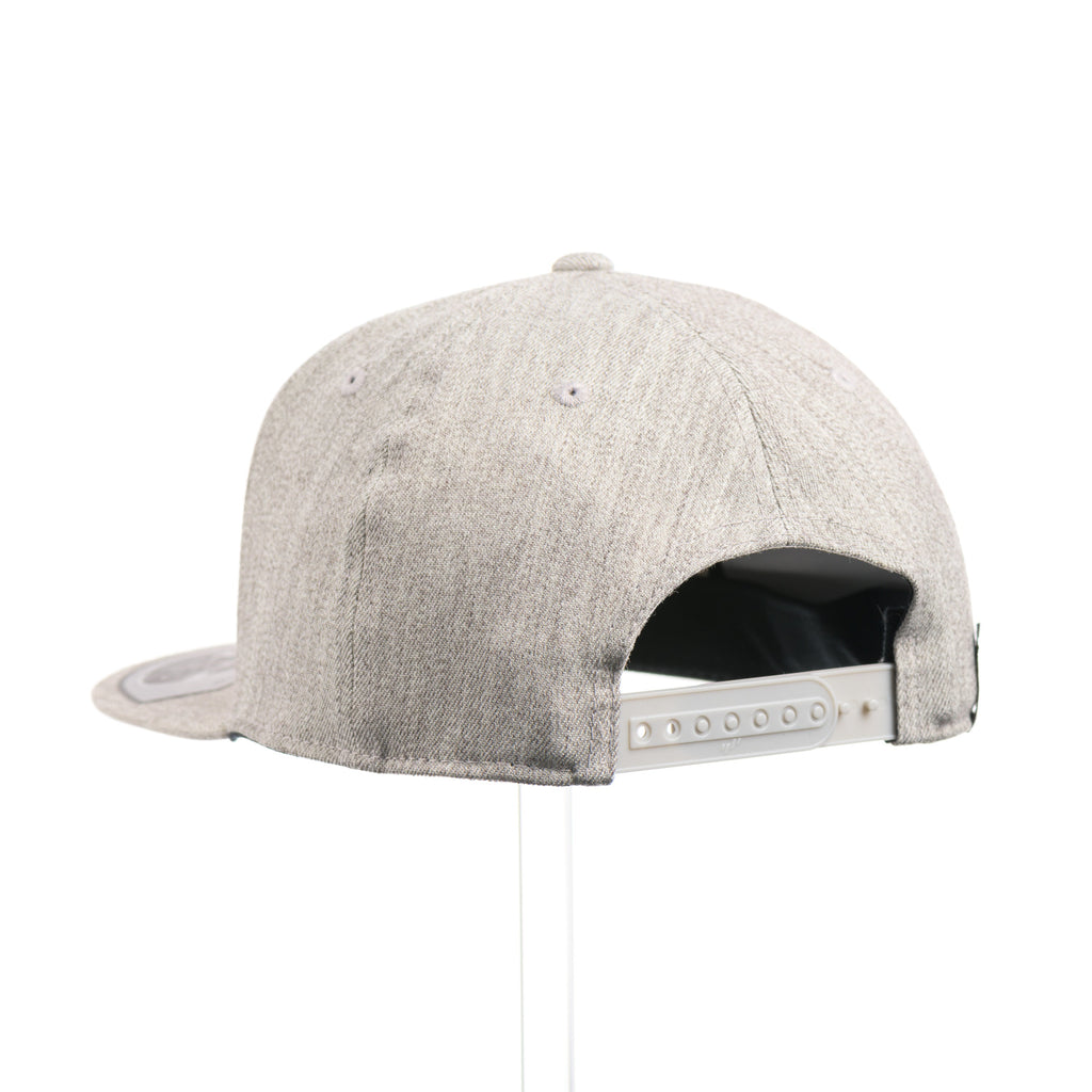 The back of a Heather Grey Flexfit Flat Bill hat with a cut out walnut wood trout patch on a black metal plate.