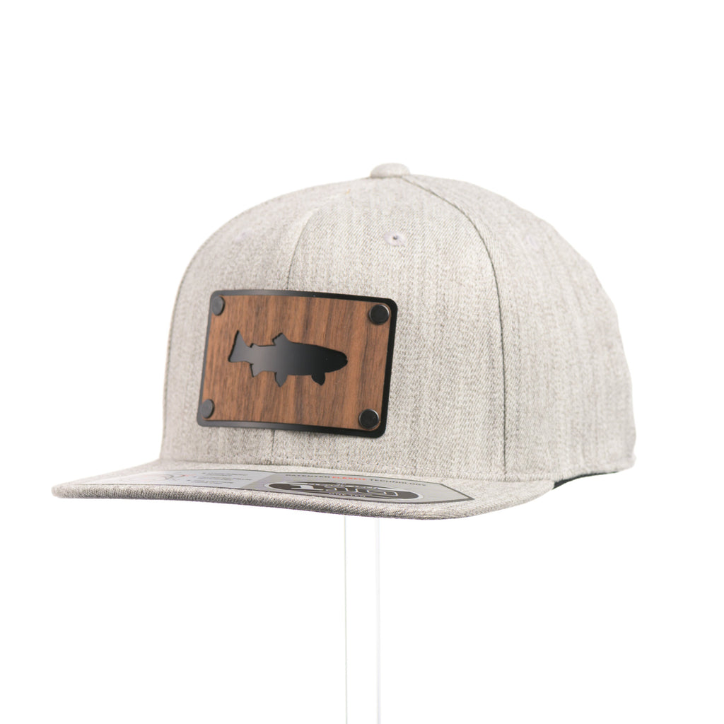 A Heather Grey Flexfit Flat Bill hat with a cut out walnut wood trout patch on a black metal plate at a quarter turn.